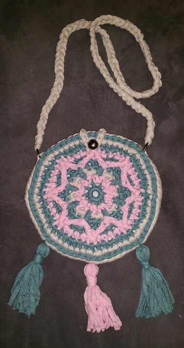 Runde gehäkelte Umhängetasche in Pastellfarben mit drei Quasten und geflochtenem Riemen
