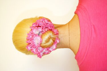 Rückansicht: blonder Dutt mit großem pink-weiß gehäkeltem Haargummi.