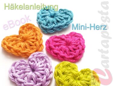 Fünf gehäkelte Mini-Herzen in Orange, Blau, Pink, Lila und Gelb auf hellem Hintergrund mit dem Text ‚Häkelanleitung eBook Mini-Herz‘