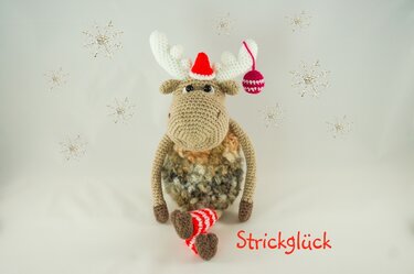 Gehäkeltes Amigurumi-Elch mit roter Weihnachtsmütze und gestreiften Socken vor hellem Hintergrund