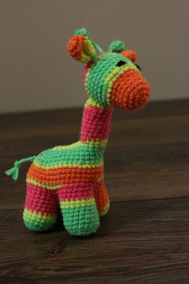 Gehäkelte Amigurumi-Giraffe mit gestreiftem Muster und kleinem Schweif