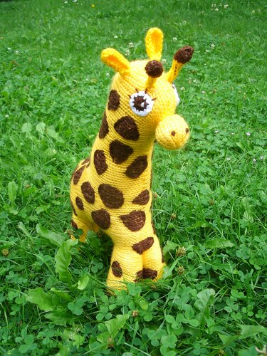 Gelb-braune Amigurumi-Giraffe, stehend im Gras