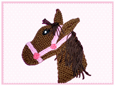 Gehäkelter brauner Pferdekopf mit rosa Zaumzeug und dunkler Mähne als Applikation