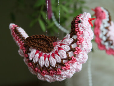 Gehäkelter Amigurumi-Vogel in Rosa, Weiß und Braun an Aufhängung, Nahaufnahme