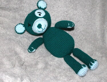 Gehäkelter Amigurumi-Teddybär dunkelgrün mit hellblauen Akzenten