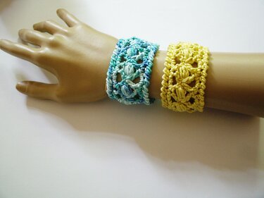 Zwei gehäkelte Armbänder in Türkis und Gelb an einer Schaufensterhand