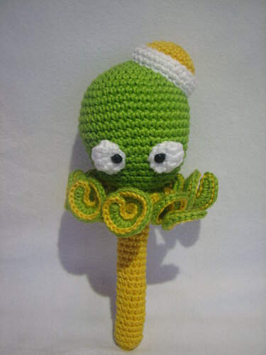 Grüne gehäkelte Baby-Rassel in Oktopusform mit gelbem Griff