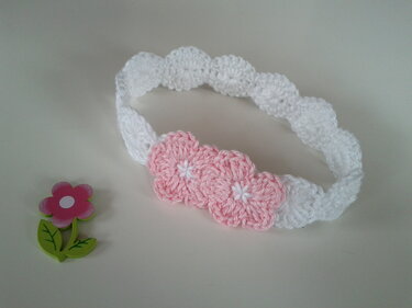 Weißes gehäkeltes Baby-Stirnband mit drei rosa Blüten und weißen Blütenmitten