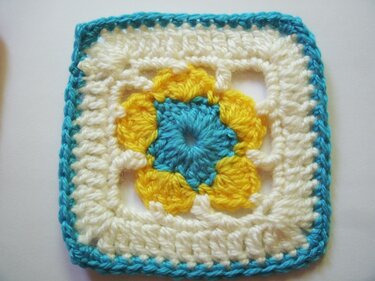 Gehäkeltes Granny
‑Square in Türkis, Gelb und Creme mit Blumenmuster