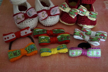 Gehäkelte Babyschuhe in Weiß und Rot und bunte Zierschleifen mit Applikationen: Waldtiere, Pilze, Punkte, Sterne.