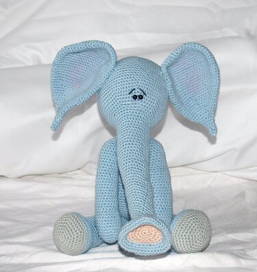Nahaufnahme eines hellblauen gehäkelten Amigurumi‑Elefanten von vorne, betonte Ohren und Rüssel