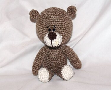 Gehäkelter brauner Teddybär mit weißer Schnauze und Pfoten, sitzend