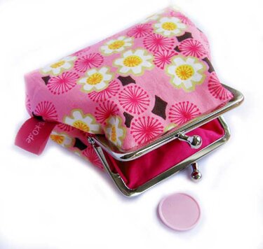 rosa Bügel-Geldbörse mit weiß-gelben Blüten, geöffnet, Metallbügelverschluss, Münze daneben