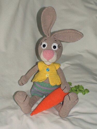 Fröhlicher gehäkelter Osterhase mit gelber Weste und Karotte