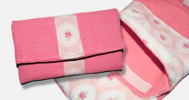 Gefaltetes rosa Portemonnaie, teilweise geöffnet, mit Blumenmusterstreifen und floralem Innenfutter