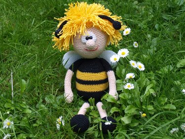 Gehäkeltes Bienen-Amigurumi mit gelben Haaren und kleinen Flügeln im Gras