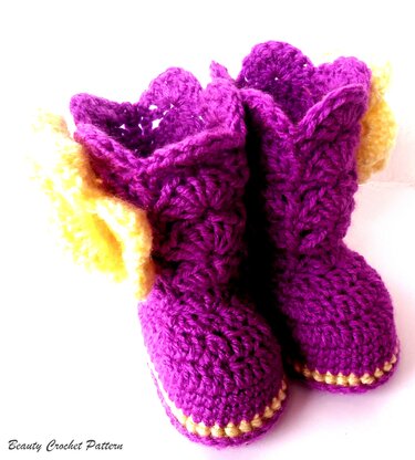 Zwei handgehäkelte Babyschuhe in Lila mit gelben Details auf weißem Hintergrund