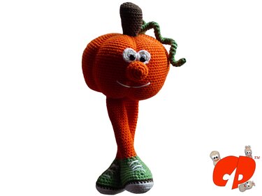 Gehäkelter orange Kürbis-Amigurumi mit langen Beinen, grünen Turnschuhen, braunem Stiel und gedrehter Ranke