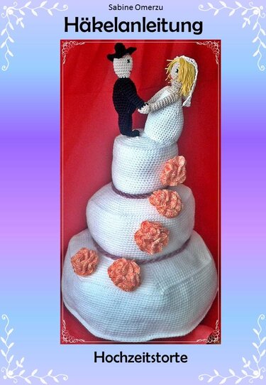 Gehäkelte dreistöckige Hochzeitstorte mit Amigurumi-Brautpaar und orangefarbenen Blüten vor rotem Hintergrund