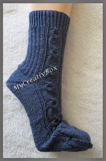 Detailansicht blau gestrickter Socke mit Zopf, Rippbündchen und geformter Ferse