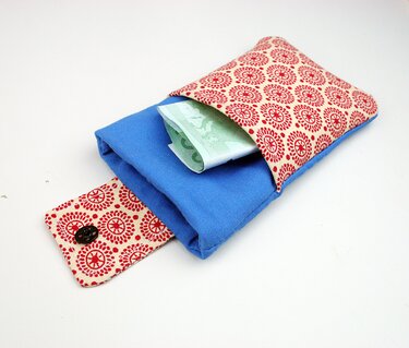 Kleines blaues Täschchen mit rot-beiger gemusterter Klappe und Knopf