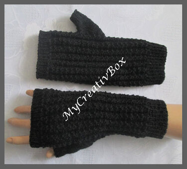 Schwarze, gestrickte Armstulpen mit Daumenöffnung, einer getragen, einer flach liegend.