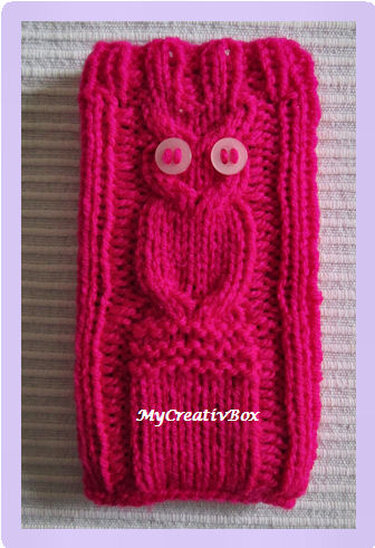 Gestricktes Etui in Fuchsia mit Eulenmotiv und zwei runden, hellen Knöpfen als Augen, auf hellem Hintergrund liegend.