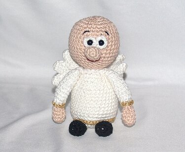 Gehäkeltes Engelchen Amigurumi in Weiß mit goldenen Zierfäden, beigem Kopf und schwarzen Schuhen