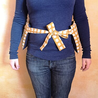 Breites gelb-weißes Bindeband um die Taille, vorne zur Schleife gebunden