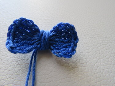 kleine gehäkelte blaue Schleife aus Garn auf hellem Untergrund