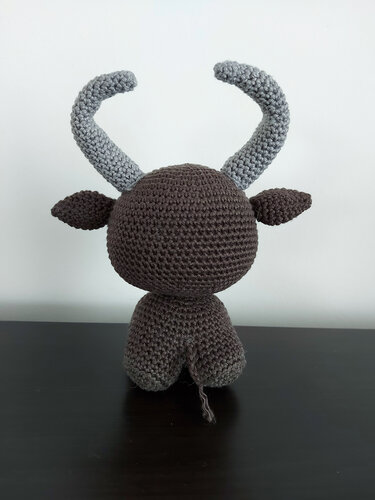 Rückansicht eines gehäkelten Amigurumi-Stiers, brauner Körper und graue Hörner