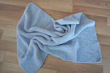 Hellgraue gestrickte Babydecke auf Holzfu
fu
boden, locker drapiert