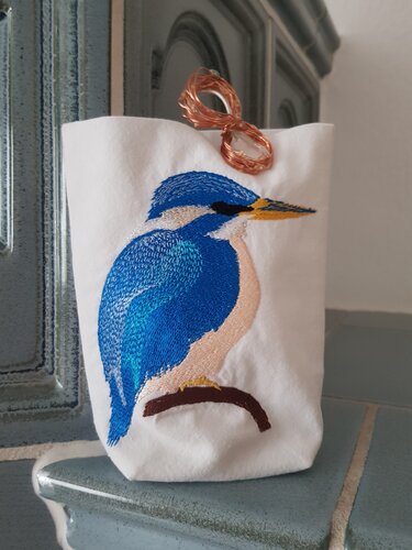 Weißer Stoffbeutel mit gesticktem blauen Eisvogel auf Ast und zarter Lichterkette