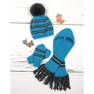 Gestricktes Baby-Set in Türkis mit Bommelmütze, Schal mit Fransen und Fäustlingen auf weißem Holzuntergrund.