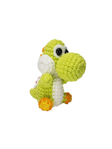 Gehäkelte grüne Amigurumi-Figur eines dinosaurierähnlichen Wesens mit weißem Bauch und orangefarbenen Füßen vor weißem Hintergrund.