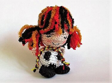 Gehäkelte Amigurumi-Puppe mit Fußballmuster und rot-orange-schwarzen krausen Haaren