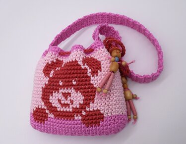 Kompakter gehäkelter Shopper in Rosa mit kurzem Trageriemen, Bärenmotiv und Holzperlenanhängern