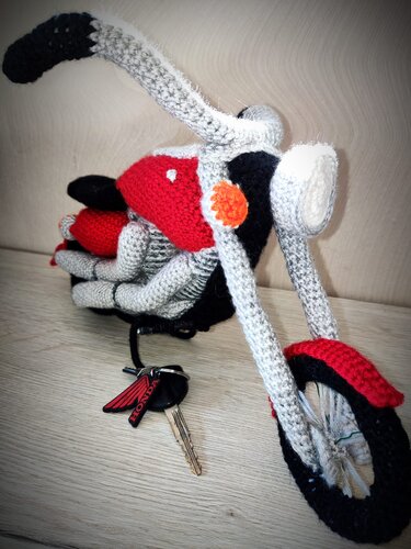 Gehäkeltes Amigurumi‑Motorrad in Rot, Grau und Schwarz mit Schlüsseln im Vordergrund