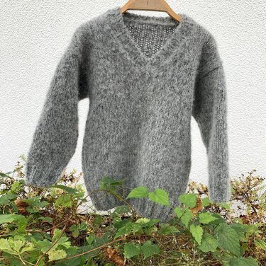 Flauschiger grauer Kinderpullover an Kleiderbügel mit sichtbarer Maschenstruktur