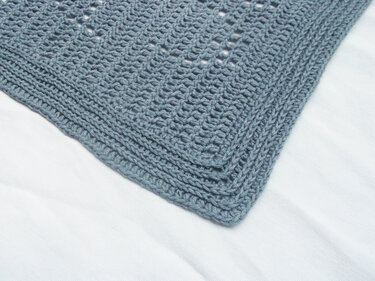 Close-up of dusty blue crochet baby blanket border and corner stitches