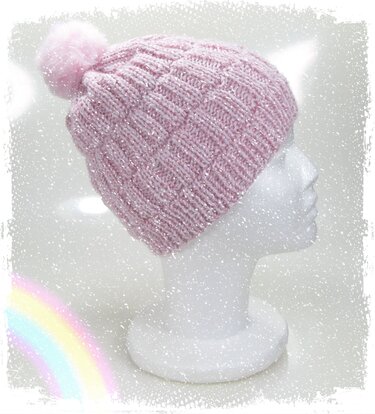 Rosa Strickmütze mit Bommel und Glitzergarn auf weißem Styroporkopf, Seitenansicht