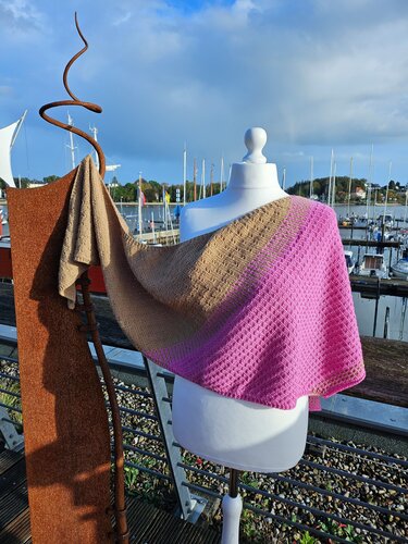Gestricktes Dreieckstuch in Pink und Beige auf einer Schaufensterpuppe vor einem Hafen