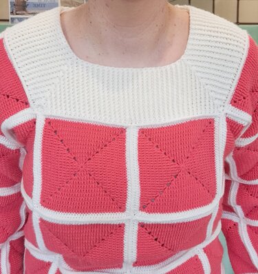 Gehäkelter Damenpullover in Korallenrot und Cremeweiß mit großen Quadraten und eckigem, geripptem Halsausschnitt.