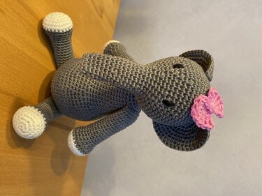 Schnell gehäkelter grauer Elefant mit weißen Füßen und rosa Schleife