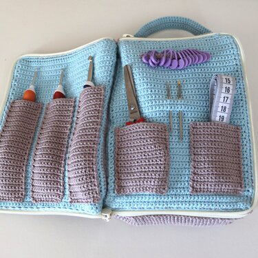 Hellblaues gehäkeltes Utensilo mit mauve Fächern und Häkelnadeln, Schere und Maßband