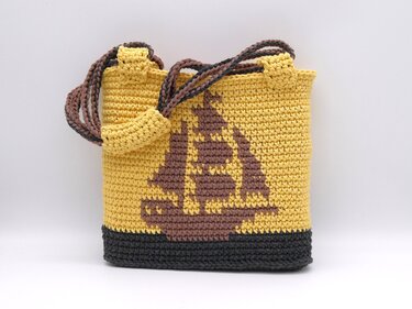 Gehäkelter gelber Shopper mit braunem Segelbootmotiv und dunklem Boden