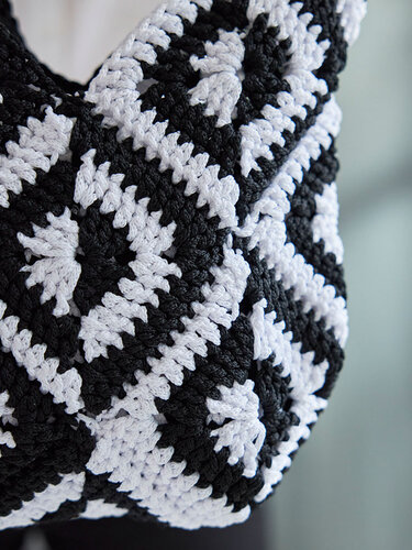 Nahaufnahme eines gehäkelten schwarz-weißen Shoppers aus Granny-Squares mit sichtbarer Maschenstruktur