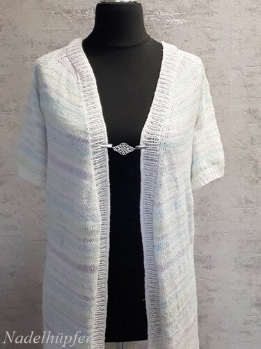 Helle offene Strickjacke mit kurzen Ärmeln auf schwarzem Büstenmannequin, Zierverschluss auf Brusthöhe