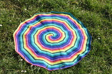 Bunte spiralförmige Häkeldecke in Regenbogenfarben auf Gras