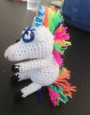 Gehäkeltes weißes Einhorn-Amigurumi mit regenbogenfarbener Mähne und Schweif, Seitenansicht